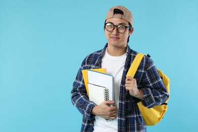 Photo of Student with backpack and notebooks on light blue background