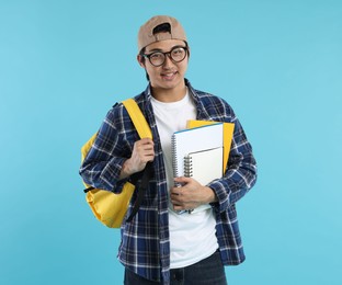 Photo of Student with backpack and notebooks on light blue background