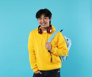 Photo of Student with headphones and backpack on light blue background
