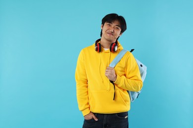 Photo of Student with headphones and backpack on light blue background