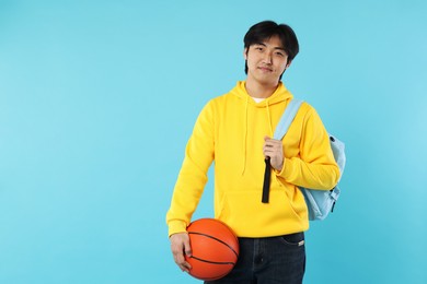 Photo of Student with basketball ball and backpack on light blue background, space for text