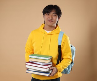 Photo of Student with books and backpack on beige background