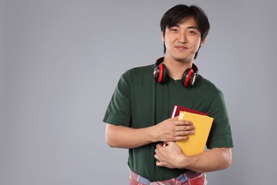 Photo of Student with headphones and books on grey background, space for text