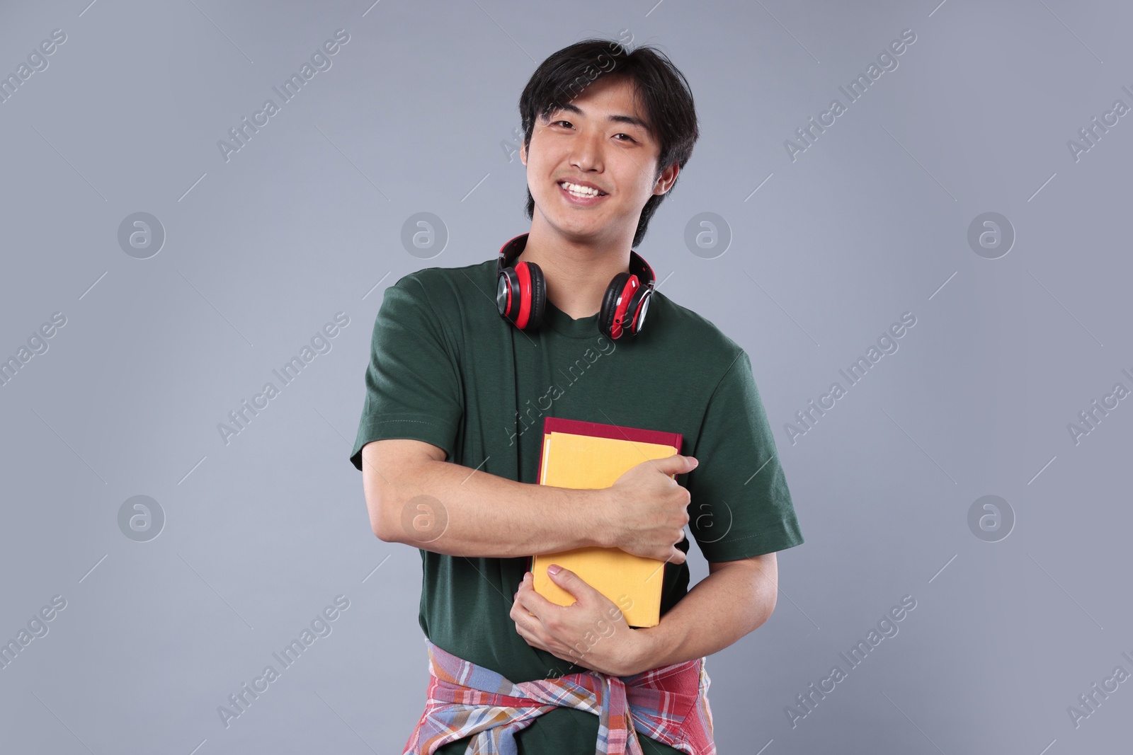 Student with headphones and books on grey background Photo of Student with headphones and books on grey background