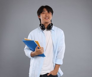 Photo of Student with headphones and notebooks on grey background