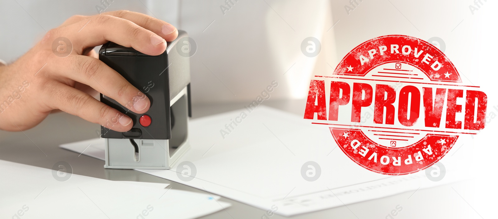 Man stamping document at desk and red stamp with word Approved. Banner design Image of Man stamping document at desk and red stamp with word Approved. Banner design