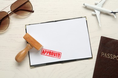 Image of Red stamp Approved in passport. Flat lay composition with toy plane, passports and wooden stamp on table