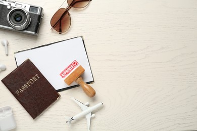 Image of Red stamp Approved in passport. Flat lay composition with toy plane, camera, passports and wooden stamp on table