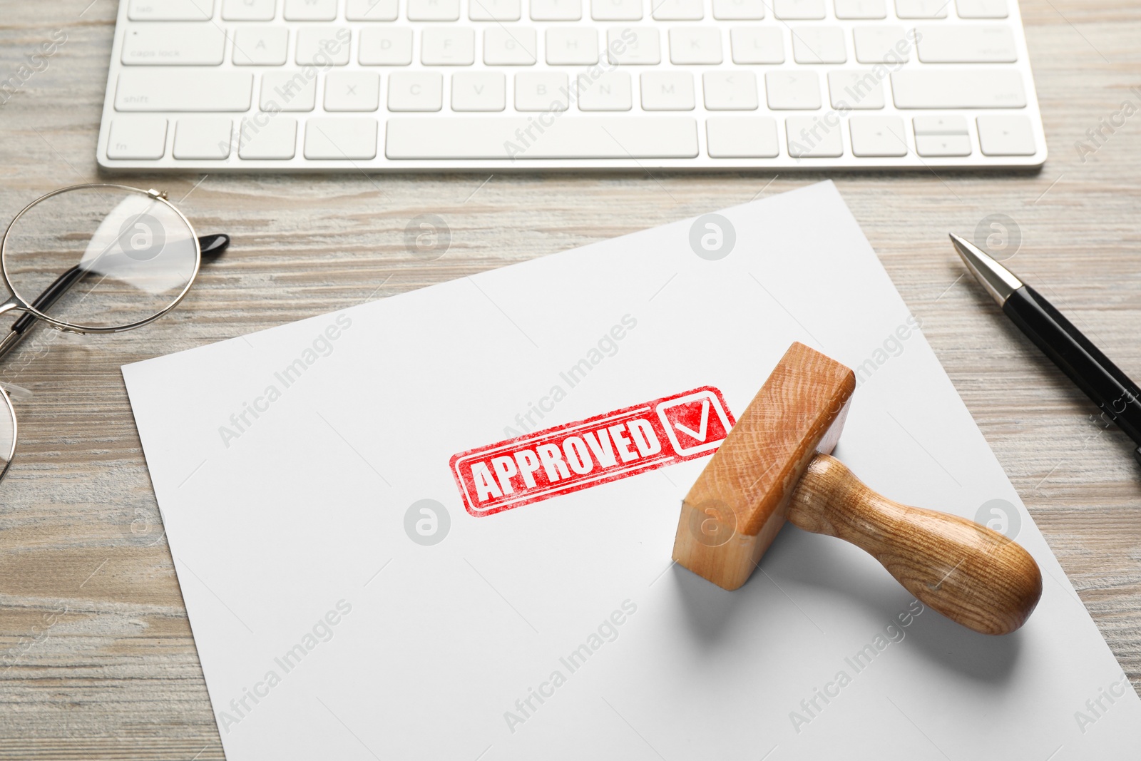 Sheet of paper with red stamp Approved and wooden stamp on table. Workplace with computer keyboard Image of Sheet of paper with red stamp Approved and wooden stamp on table. Workplace with computer keyboard