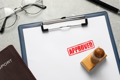 Image of Sheet of paper with red stamp Approved, passport and wooden stamp on table, closeup