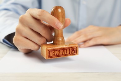 Image of Approved. Woman stamping blank sheet of paper at table, closeup