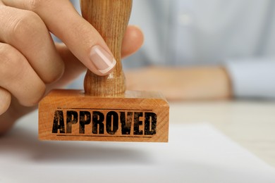 Image of Approved. Woman stamping blank sheet of paper at table, closeup