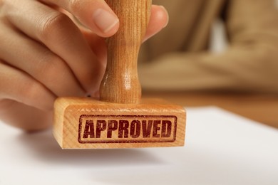 Image of Approved. Woman stamping blank sheet of paper at table, closeup