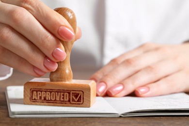 Image of Approved. Woman stamping passport at table, closeup