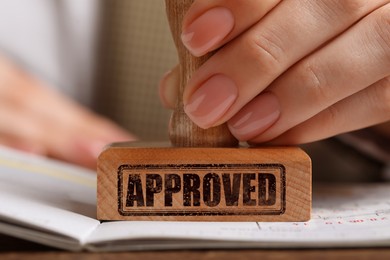 Image of Approved. Woman stamping passport at table, closeup