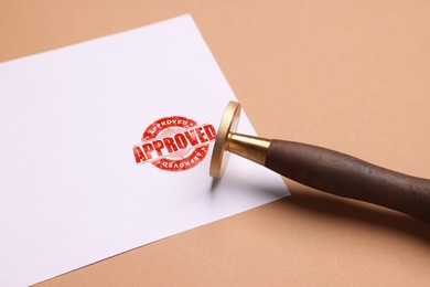 Image of Sheet of paper with red stamp Approved and stamp on pale brown background