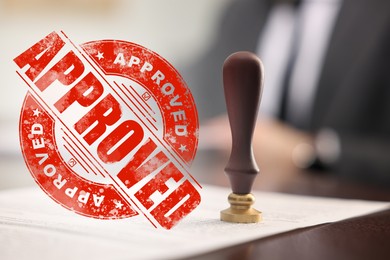 Image of Man working with document at table and red stamp Approved