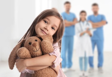 Image of Cute child holding toy bear and medical staff in hospital. Pediatric ward