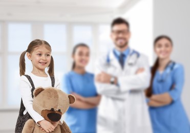Image of Cute child holding toy bear and medical staff in hospital. Pediatric ward