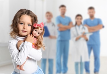 Image of Cute child holding doll and medical staff in hospital. Pediatric ward