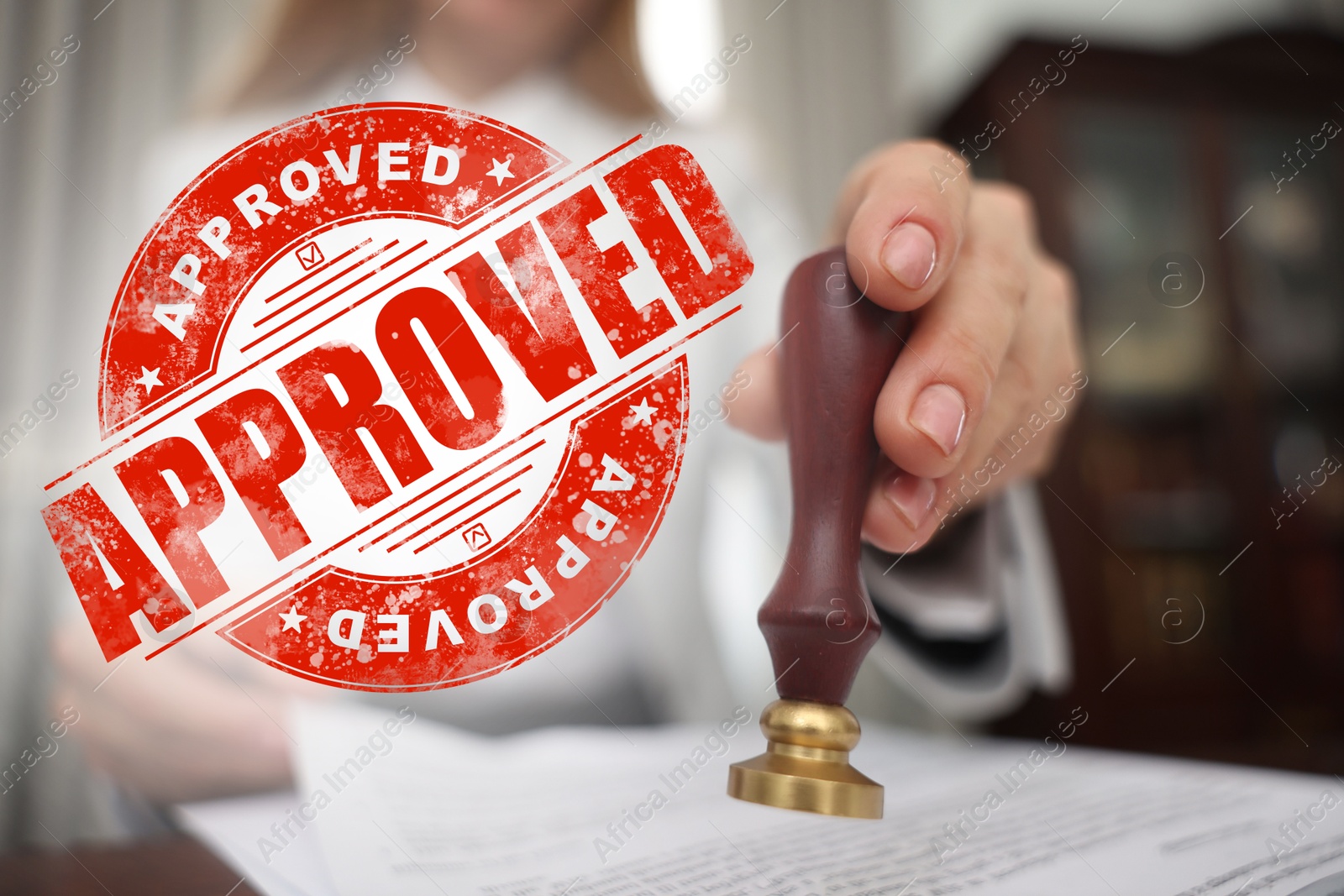 Woman stamping document at table and red stamp Approved Image of Woman stamping document at table and red stamp Approved