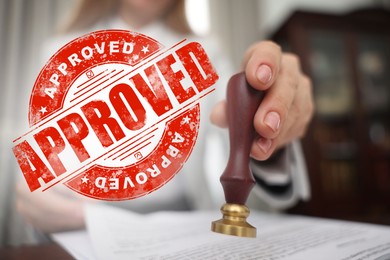 Image of Woman stamping document at table and red stamp Approved