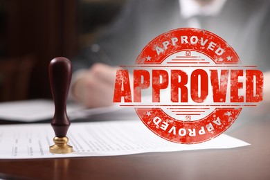 Image of Man working with document at table and red stamp Approved