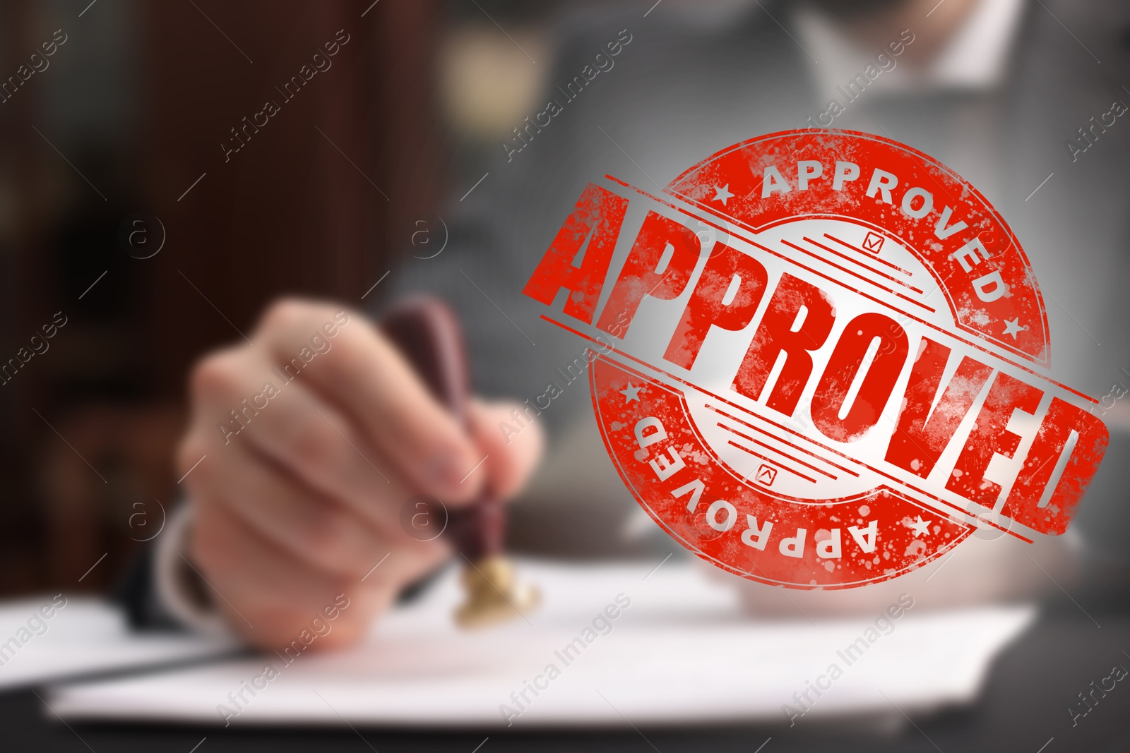 Man stamping document at table and red stamp Approved Image of Man stamping document at table and red stamp Approved