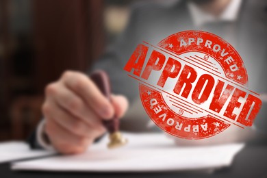 Image of Man stamping document at table and red stamp Approved