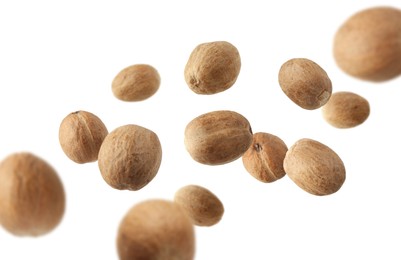 Image of Aromatic nutmeg seeds falling on white background