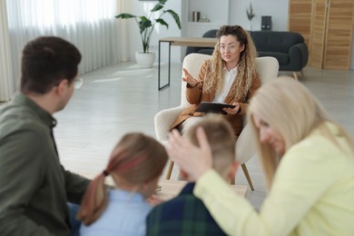 Photo of Family having consultation with psychologist in office, selective focus