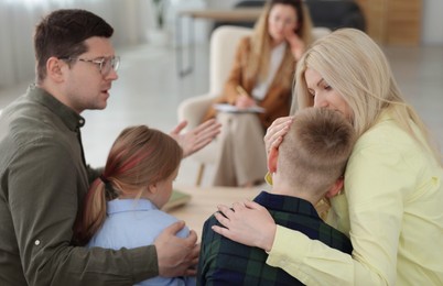 Photo of Family having consultation with psychologist in office, selective focus