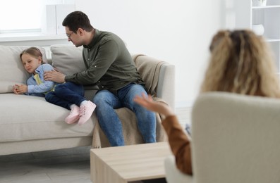 Photo of Father and daughter having consultation with psychologist in office, selective focus