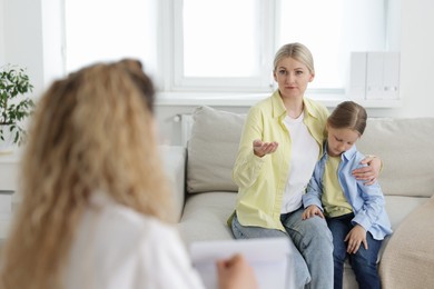 Photo of Mother and daughter having consultation with psychologist in office, selective focus