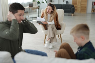 Photo of Father and son having consultation with psychologist in office, selective focus