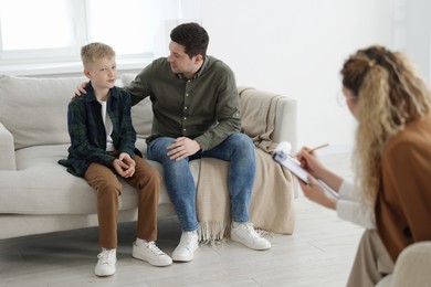 Photo of Father and son having consultation with psychologist in office, selective focus