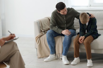 Photo of Father and son having consultation with psychologist in office, selective focus