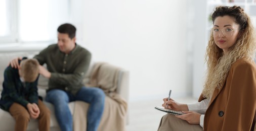 Photo of Father and son having consultation with psychologist in office, selective focus