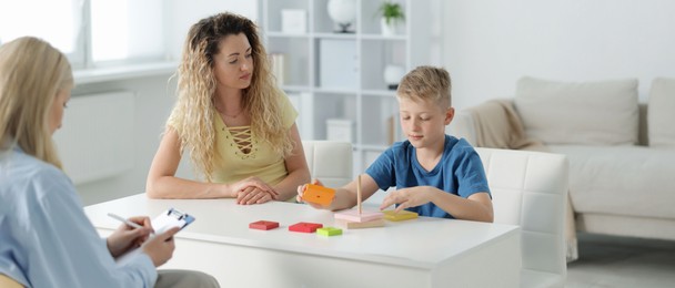 Photo of Mother and son having consultation with psychologist in office, selective focus