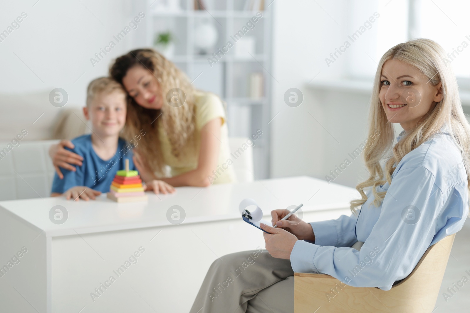 Mother and son having consultation with smiling psychologist in office, selective focus Photo of Mother and son having consultation with smiling psychologist in office, selective focus