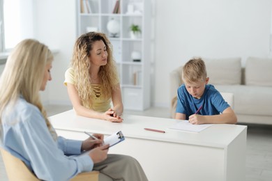 Photo of Mother and son having consultation with psychologist in office, selective focus