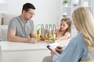 Photo of Father and daughter having consultation with psychologist in office, selective focus