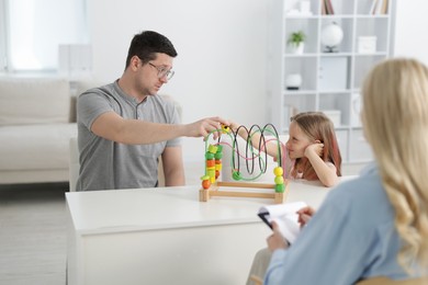Photo of Father and daughter having consultation with psychologist in office, selective focus
