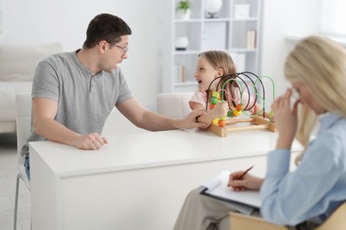 Photo of Father and daughter having consultation with psychologist in office, selective focus