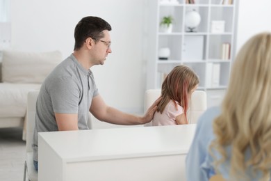 Photo of Father and daughter having consultation with psychologist in office, selective focus