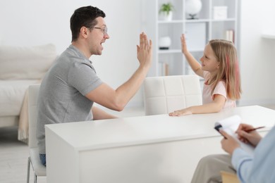 Photo of Father and daughter having consultation with psychologist in office, selective focus