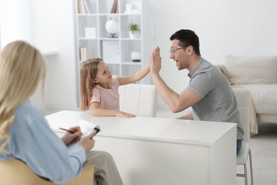 Photo of Father and daughter having consultation with psychologist in office, selective focus