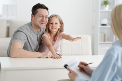 Photo of Happy father and daughter having consultation with psychologist in office, selective focus
