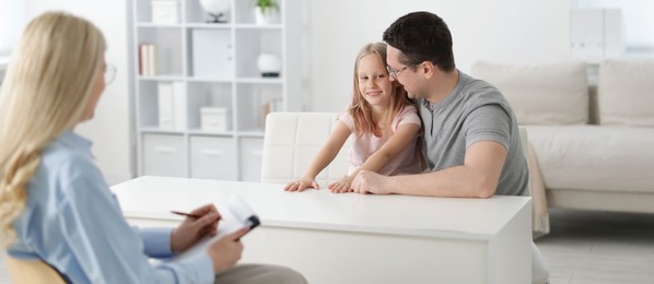 Photo of Happy father and daughter having consultation with psychologist in office, selective focus
