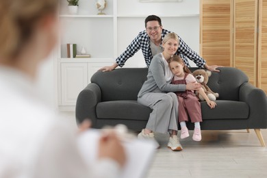 Photo of Happy family having consultation with psychologist in office, selective focus